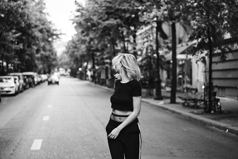 Young blonde woman walking on city street in black and white