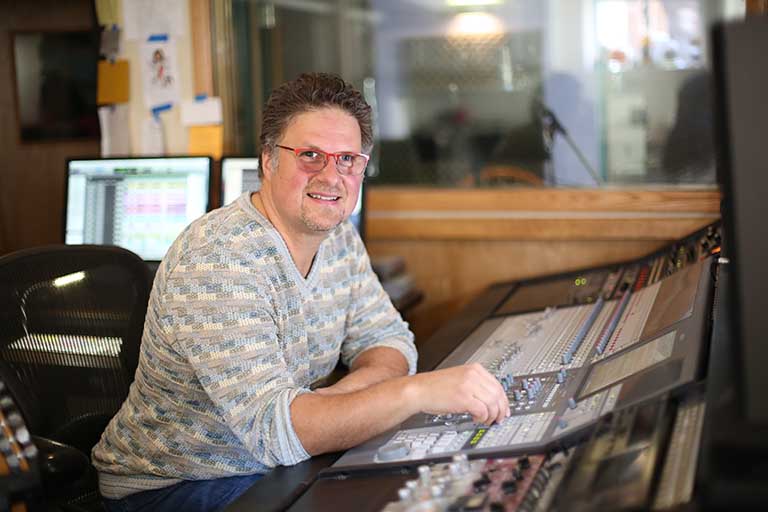 Tony DiLullo sitting at mixing board in NY Tune Saloon studio